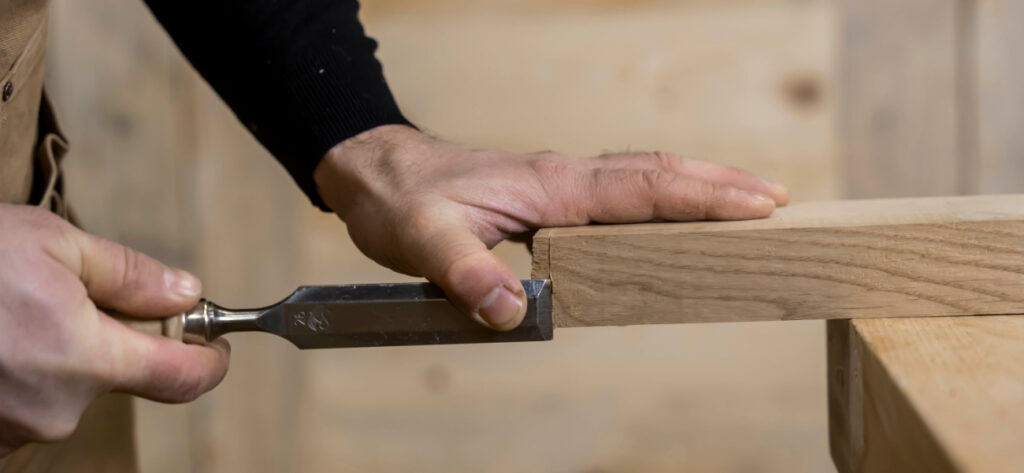 Stolarz Radosław Grabski używa dłuta do pracy z drewnem