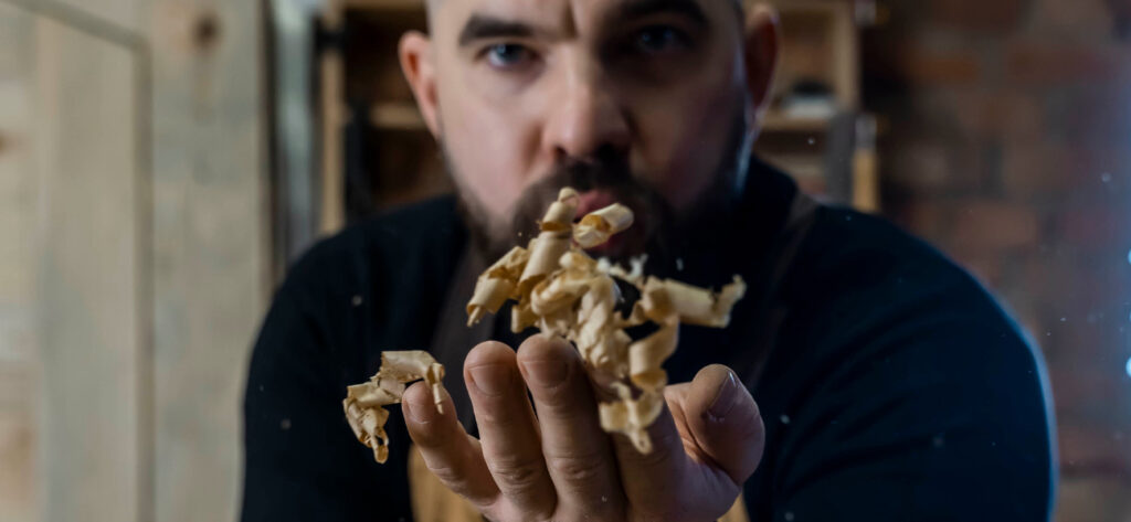 Stolarz Radosław Grabski zdmuchuje wióry drewna